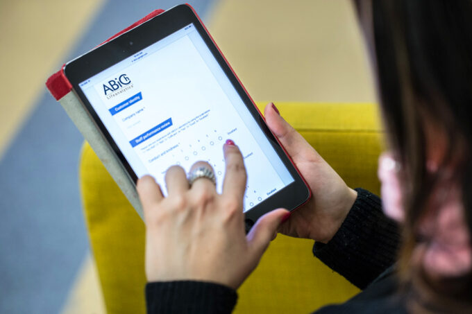 This image shows a person filling out a digital feedback form on a tablet. The form is branded with the ABICH Lifeanalytics logo and appears to be a staff performance review or customer satisfaction survey