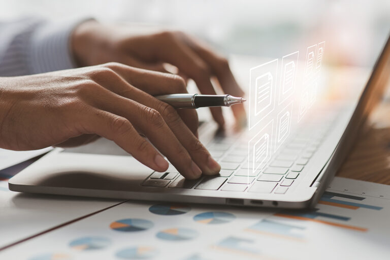 Hands typing on a laptop keyboard with digital icons.