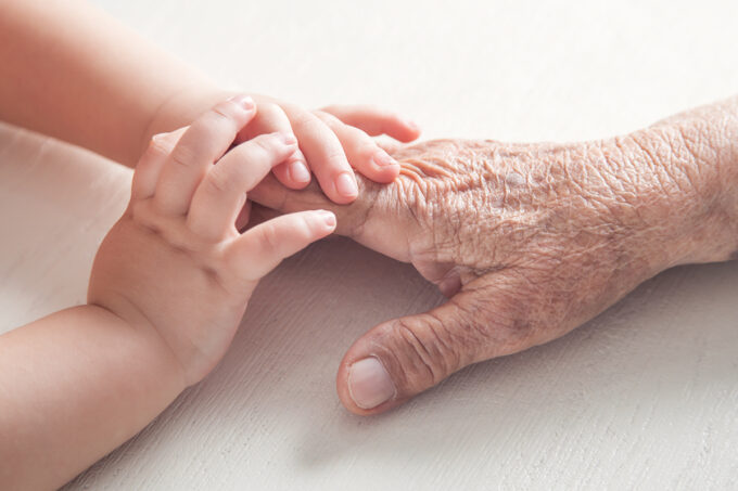 Symbol image for the article ‘Beyond beauty: how antioxidants promote skin longevity’, showing a child's hand gently holding an elderly person's hand