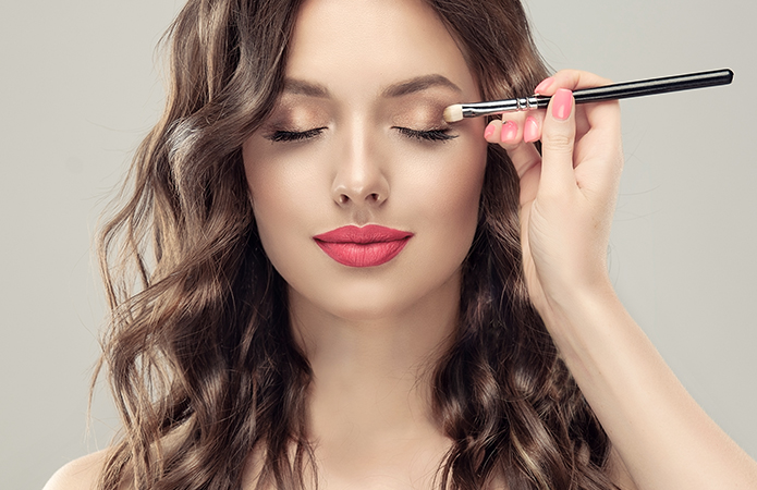 Close-up image of a woman with professional makeup applying eyeshadow with a brush, symbolizing the blog article dedicated to clinical trials in makeup: a competitive advantage because they are fundamental for beauty brands, of the cosmetic & medical device business unit of Abich_Lifeanalytics